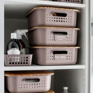 Under sink cuboard with two shelves storing baskets and cleaning items