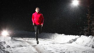A man running at night on snowy forest road – tips for trail running at night