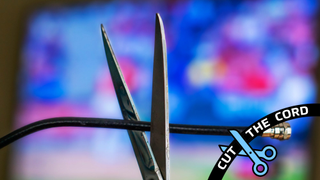 Scissors cutting a coaxial cable in front of a television