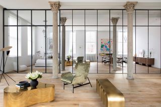 Tribeca loft by Andrea Leung features a floor to ceiling wall of mirrors with two stone pillars. The furniture features a grey chair, a pizzle like table design, a side unit with arches.