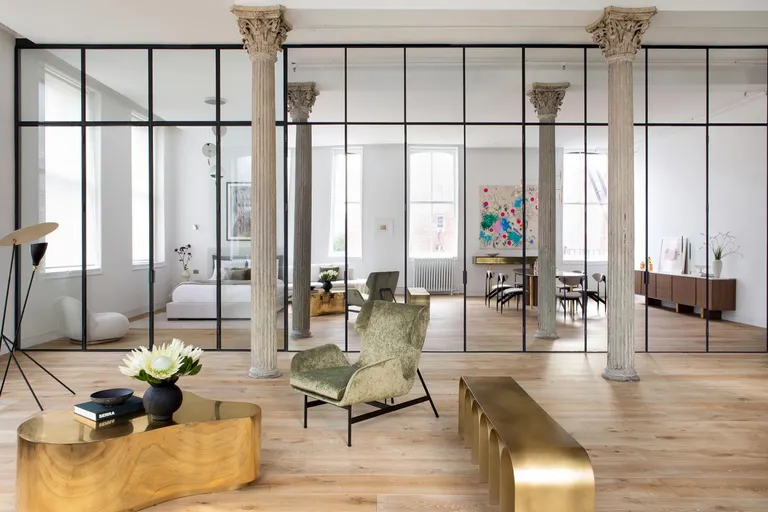 Tribeca loft by Andrea Leung features a floor to ceiling wall of mirrors with two stone pillars. The furniture features a grey chair, a pizzle like table design, a side unit with arches.