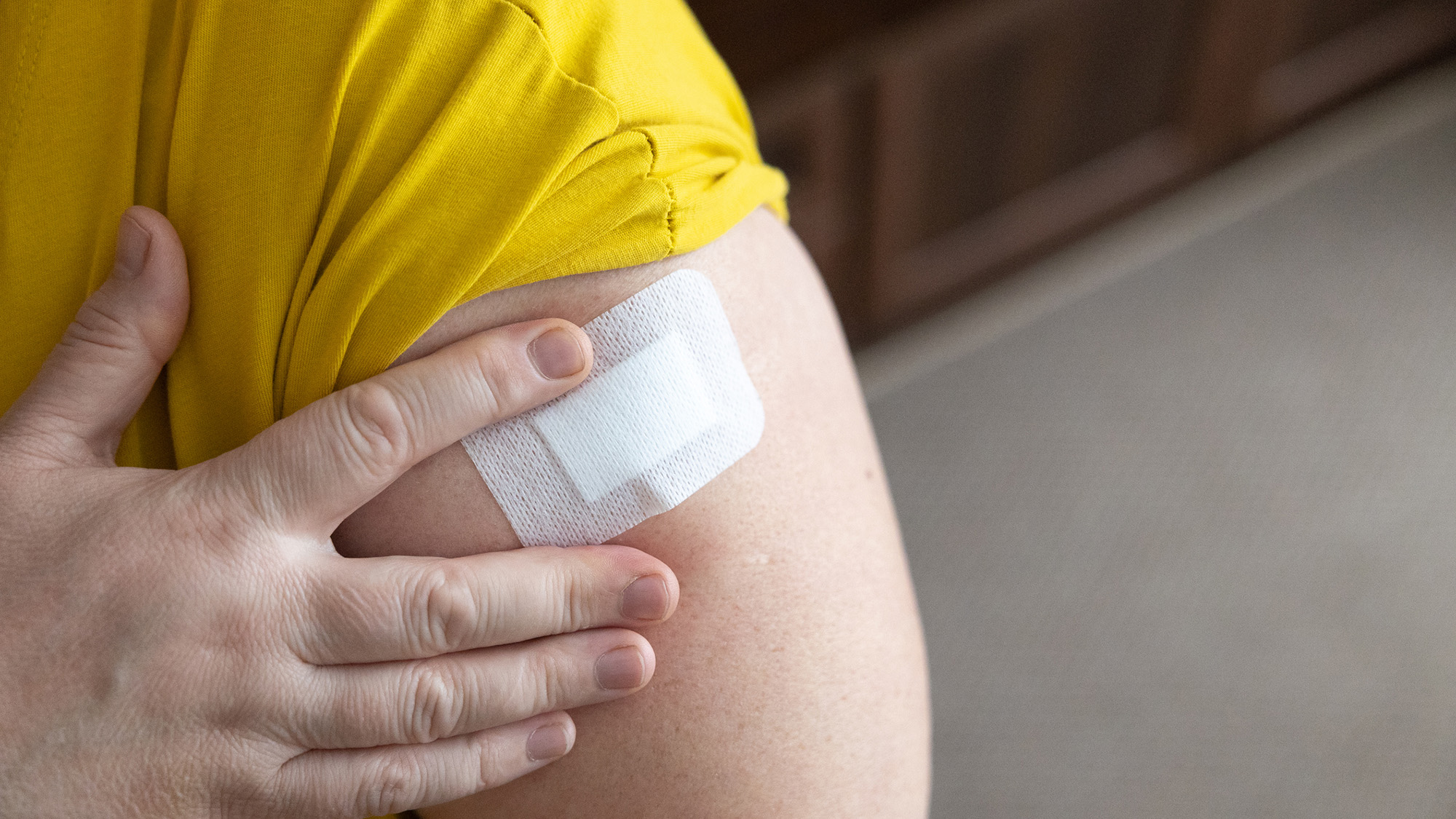 A close up of a person putting a patch on their arm.