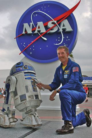 R2-D2 and NASA astronaut Jim F. Reilly posed with the lightsaber prior to the 14-day STS-120 mission.