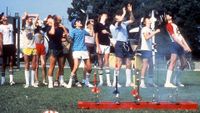 kids in multi-color t-shirts and shorts watch model rockets fly as other rockets stand ready to fly from a launch pad