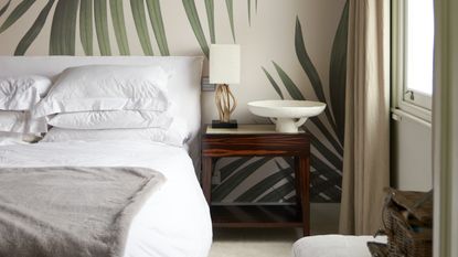 Bedroom with wallpaper accent wall and wall panelling, jewel toned bedding and houseplant