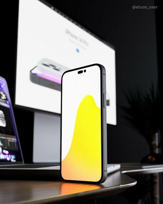 An unofficial render of the iPhone 14 Pro, stood upright on a desk with a monitor in the background