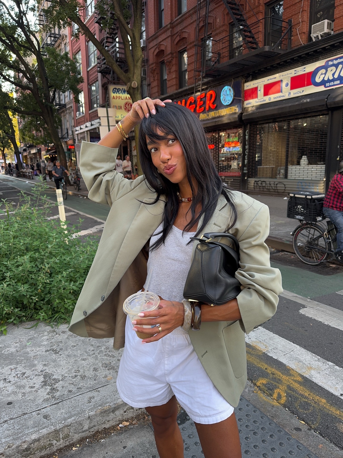 Creator @amaka.hamelijnck wearing a light green blazer in New York, posing while playing with her hair