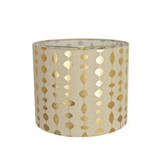 A drum lampshade with a beige background and gold geometric shapes in a striped pattern on it