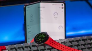 Pixel Watch 2 on keyboard with OnePlus Open in the background