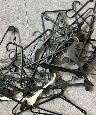 Piles of black coat hangers on grey carpet