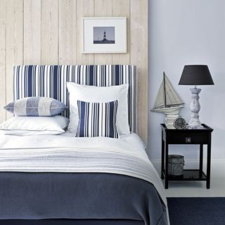 bedroom with white wall bed with white and blue cushion and frame on wooden wall