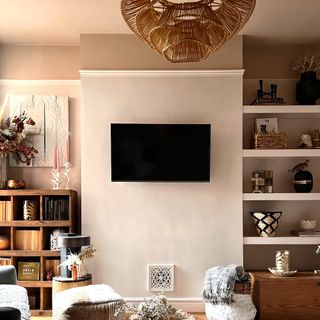 Living room with wall mounted TV, alcove shelving, and shelving unit with decorative furnishings