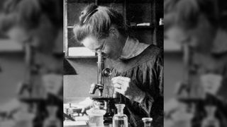 Black and white photo of American geneticist Nettie Maria Stevens looking through a microscope.