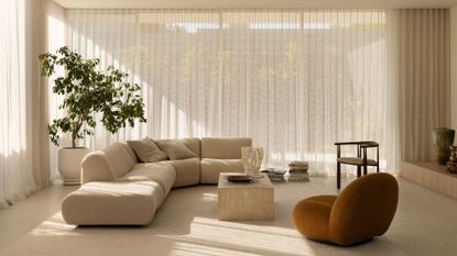 A minimalist living room with a large white couch and a mustard sofa seater, a houseplant and a neutral coffee table