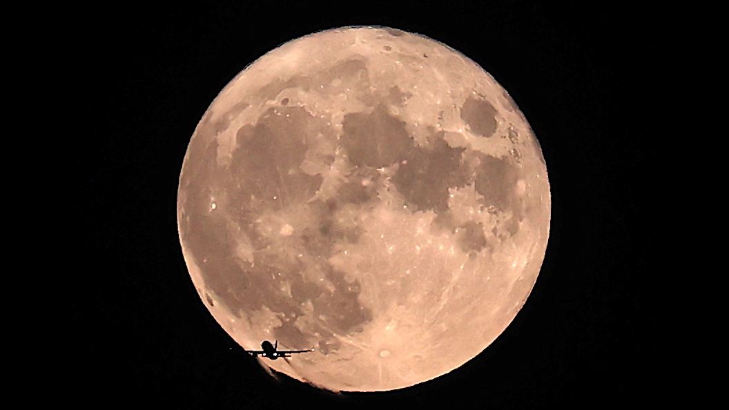 A plane flies past the full moon over Ankara, Turkey on Aug. 22, 2021.