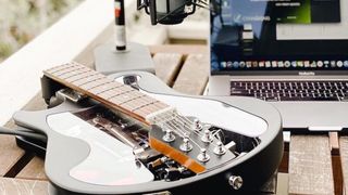 A folded Ciari Ascender guitar on a table, next to a laptop