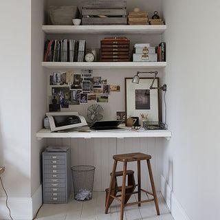 books in white wall shelf wooden table and photos on wall
