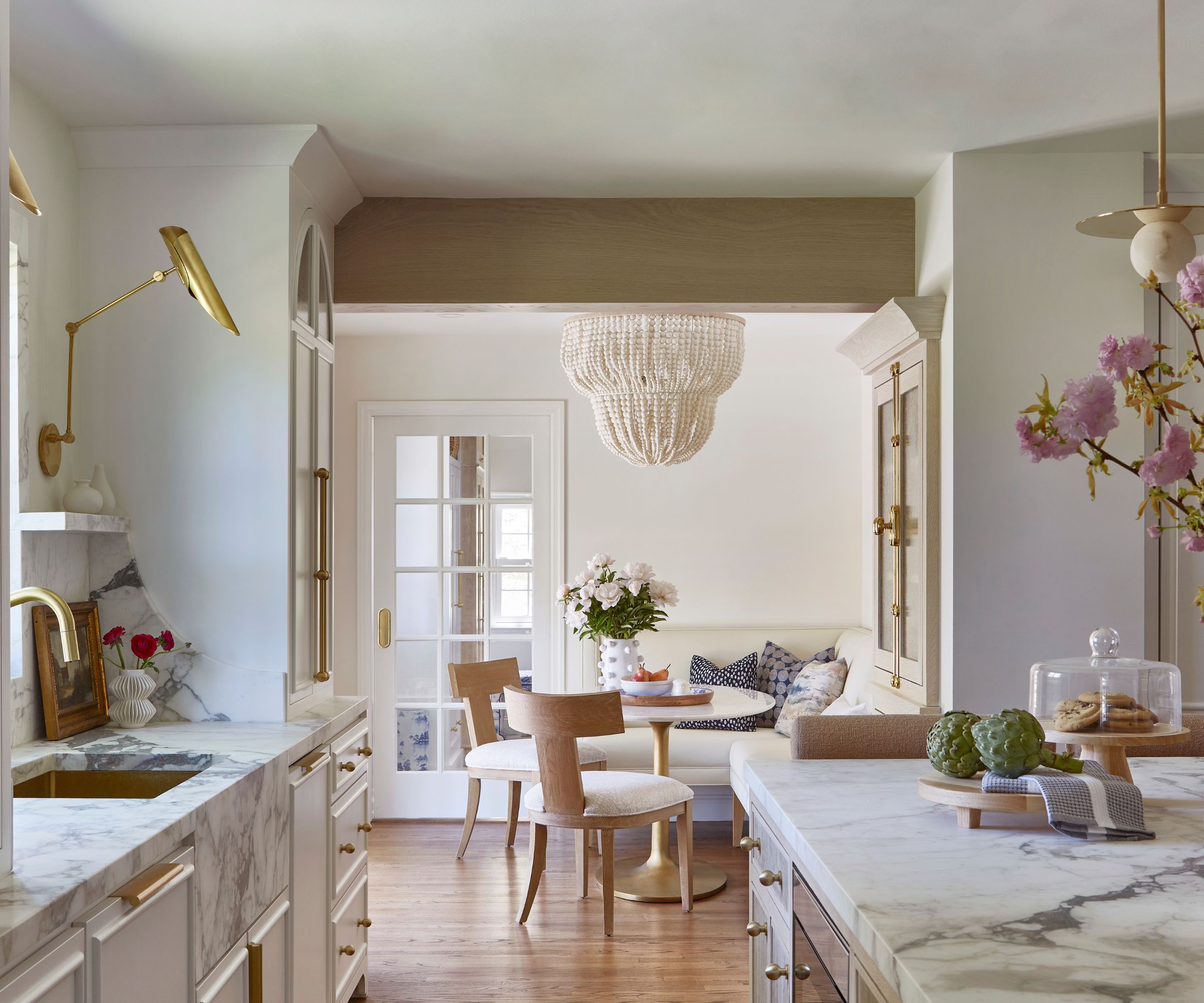 A white kitchen with marble countertops and a banquette seating area