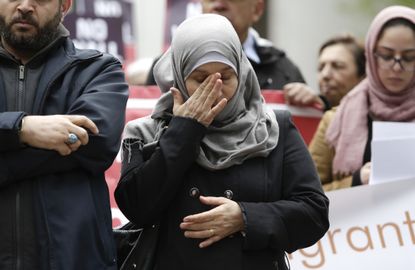 A Syrian refugee wipes her eyes at a rally protesting President Trump's travel ban.