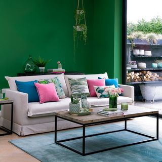 living area with green wall and wooden fl;oor and sofa with cushions and coffee table