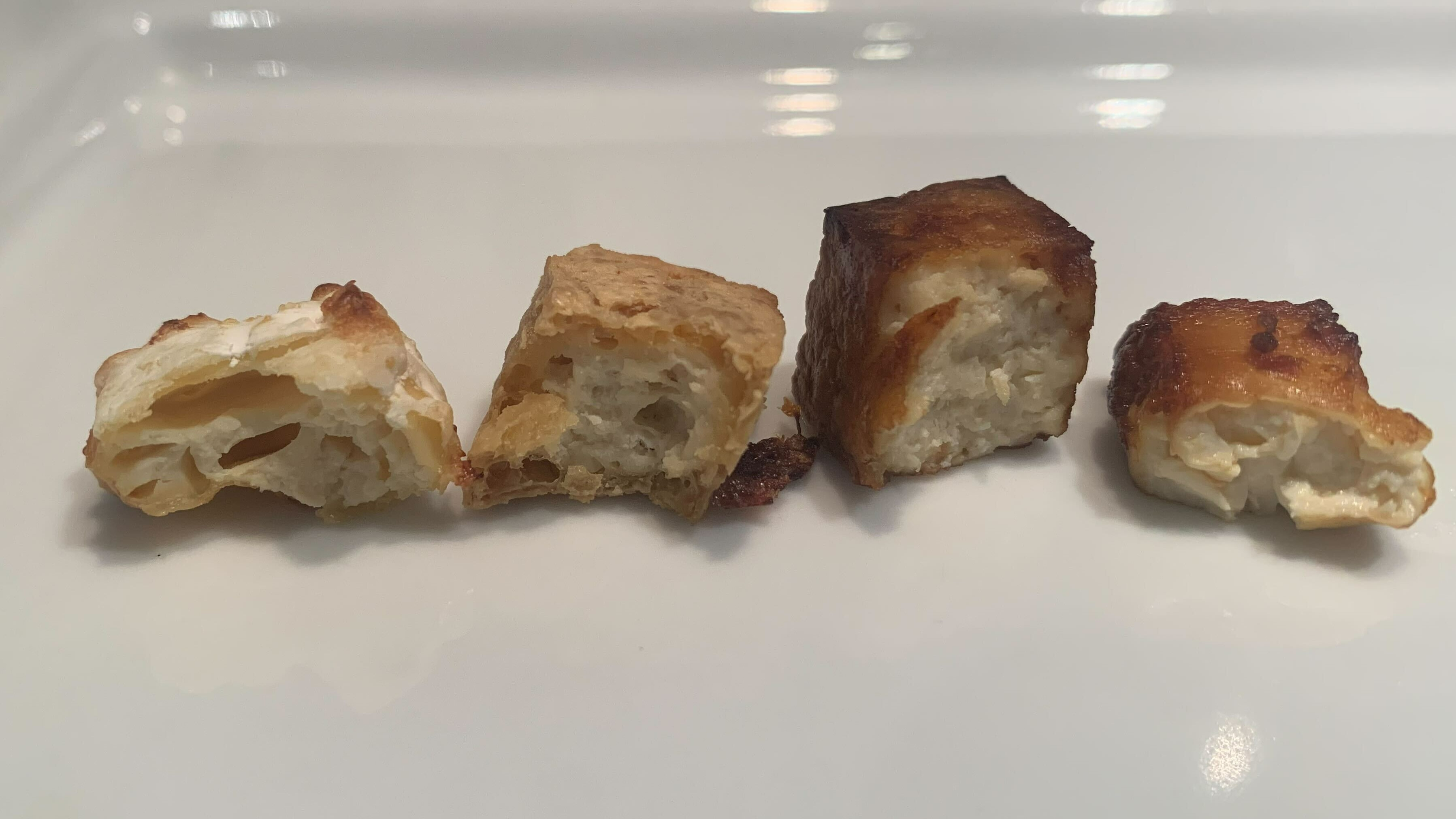 Cooked tofu, from left to right; silky unseasoned tofu with cornstarch, unseasoned spongy tofu, seasoned spongy tofu and finally the seasoned silky tofu.