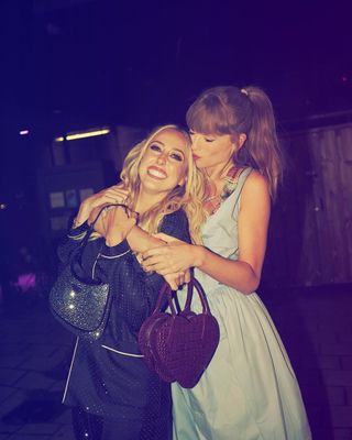 Taylor Swift with Brittany Mahomes wearing a blue Vivienne Westwood dress and a heart-shaped bag.