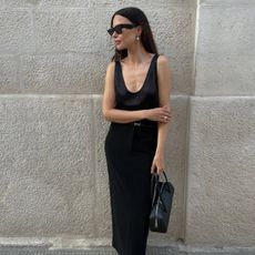 Influencer Johanna Piispa wears a maxi black skirt and a silky scoop neck blouse. 