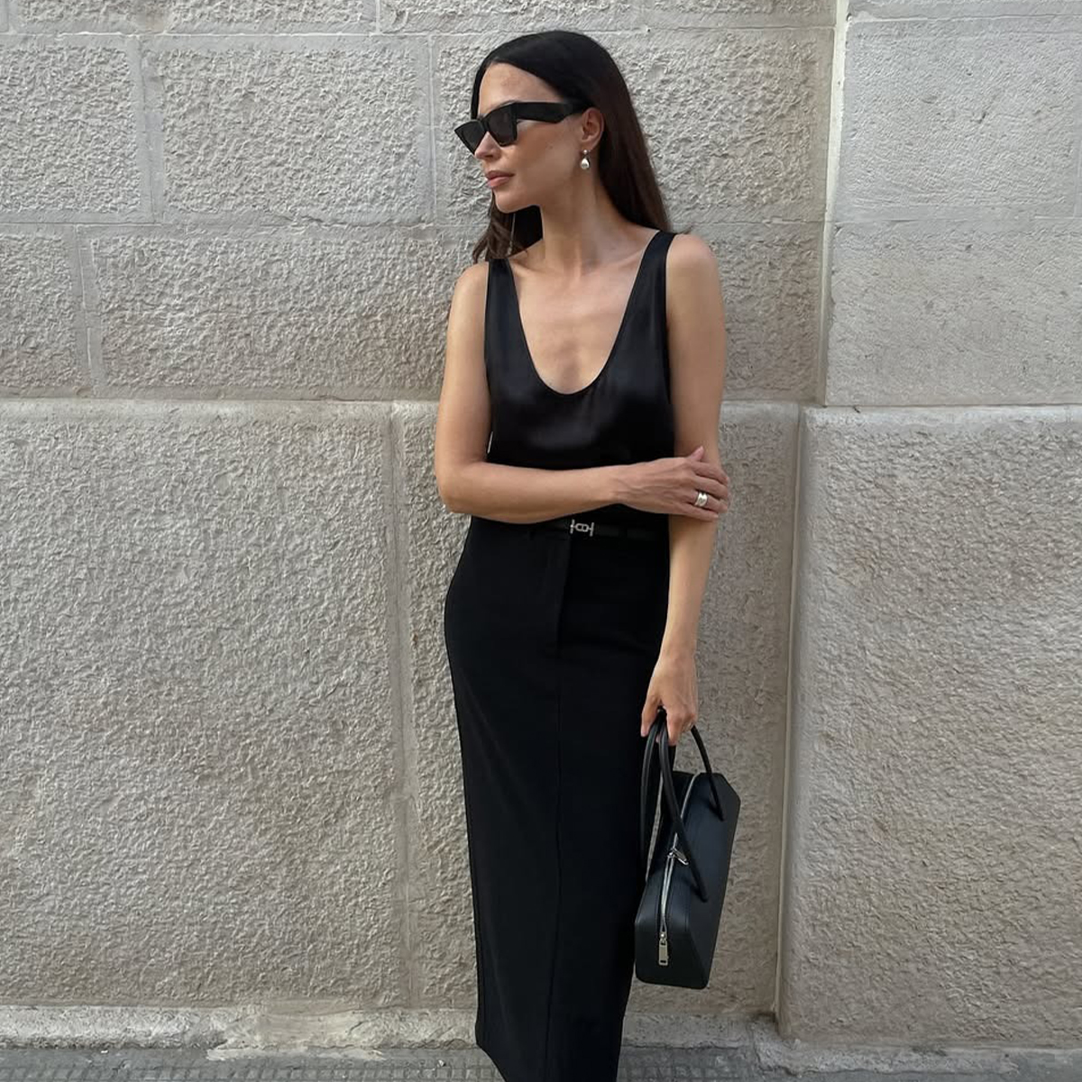Influencer Johanna Piispa wears a maxi black skirt and a silky scoop neck blouse. 