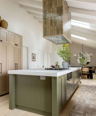 Luxurious kitchen island with tiled oven hood and green cabinets