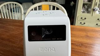 BenQ GV31 home cinema projector on wooden table close up on lens aperture