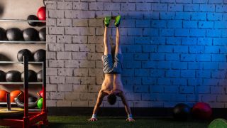 Man performs handstand against wall