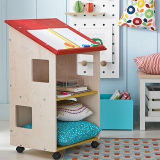 A children's playroom with a storage caddy on wheels shaped like a house