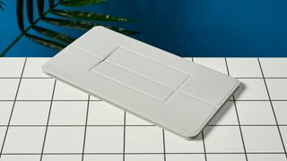 the soft smooth cover of a white, lightweight tablet keyboard made by mokibo rests upon a white tiled table with a blue background