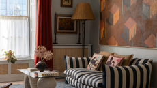 a maximalist living room with a striped couch, a large artwork on the wall, a decorative coffee table, and a tall lamp in the corner