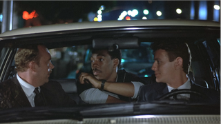 Eddie Murphy, Judge Reinhold, and John Ashton in a car talking in Beverly Hills Cop