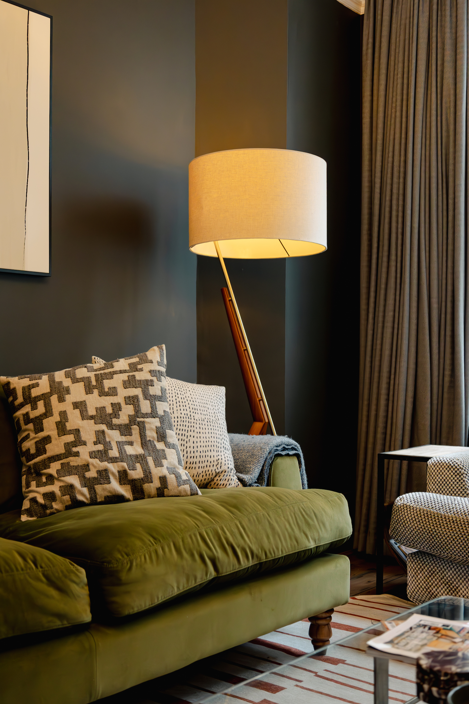 A living room with green sofa, and a lamp with warm yellow light