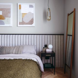 Bedroom painted light gray with wall art, light gray bedding and green throws