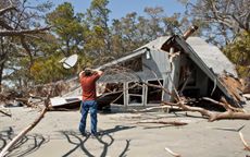 picture of a man standing in front of a destroyed house