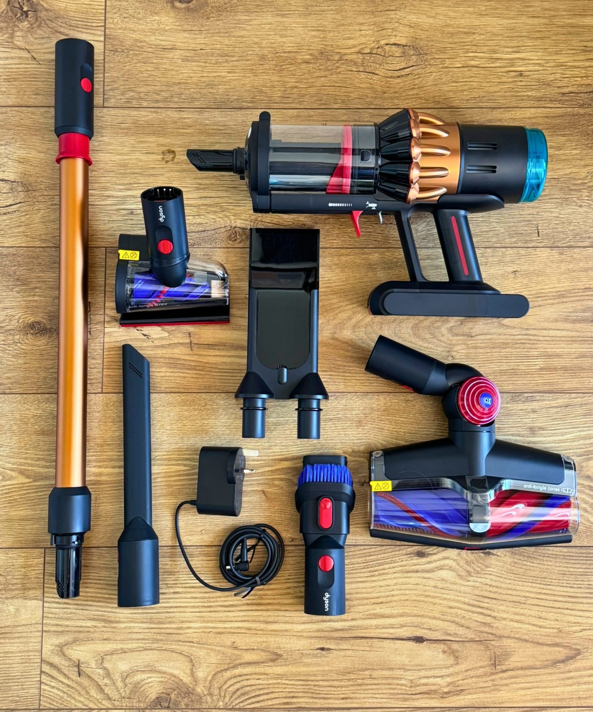 All parts and attachments of the Dyson V16 Piston Animal laid out on wooden floor.