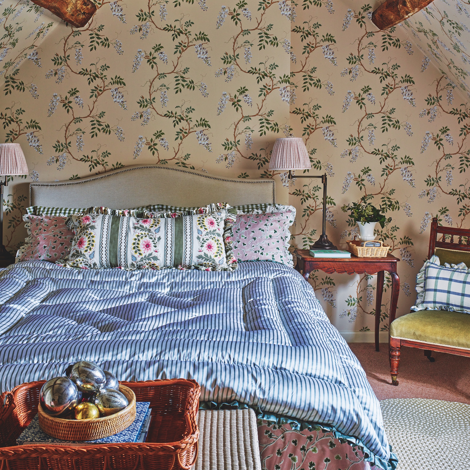 attic bedroom decorated with floral wallpaper and double bed with silk sheets