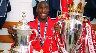 LONDON, ENGLAND - MAY 11: Sol Campbell of Arsenal with the FA Cup Trophy and the Premier League Trophy after the Premier League match between Arsenal and Everton on May 11, 2002 in London, England. (Photo by Stuart MacFarlane/Arsenal FC via Getty Images)