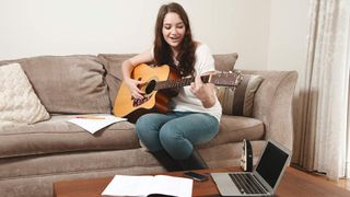 Woman playing a Fender beginner acoustic guitar at home