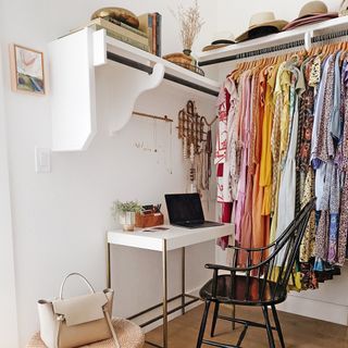 White desk inside walk-in closet with colorful clothes