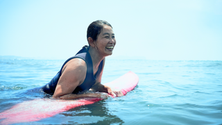 Woman catching breath on surfboard