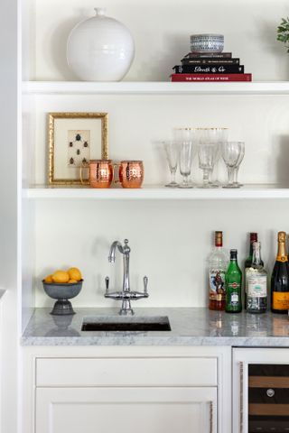 white shelving with home bar and sink built in and bottles