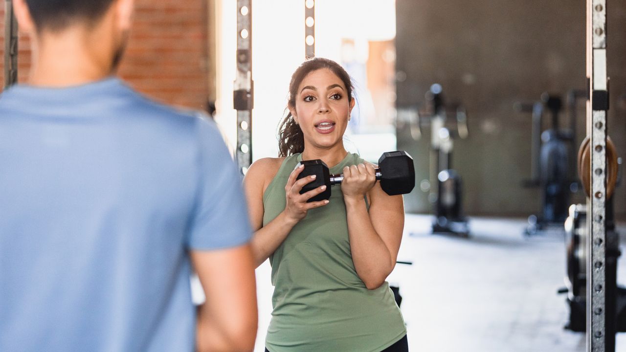 A trainer demonstrating a dumbbell exercise