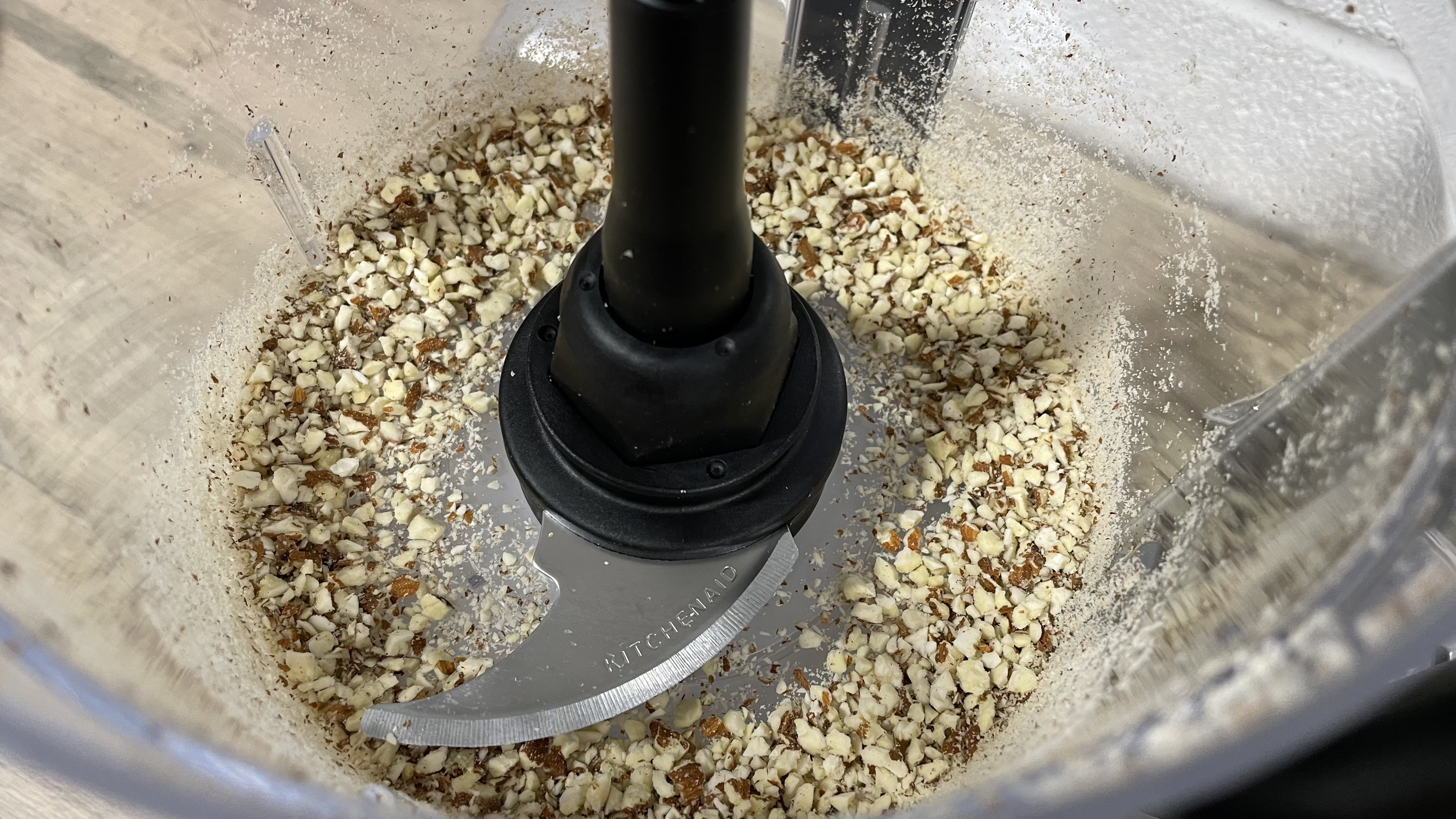 A close up view of chopped almonds inside the workbowl of the KitchenAid Mini Food Chopper.