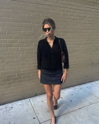 Robin Reetz wears a black cardigan with a mini skirt and square-toe flats.