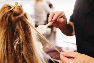 hairdresser putting hair dye on woman's head