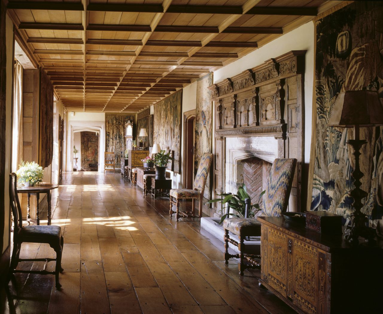 The Long Gallery at Packwood House shows the fireplace, late C17th Italian chairs covered in English bargello needlework, oak floor and tapestries.